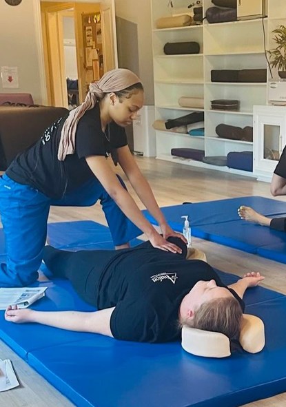 Holly O'Neal guiding a leg stretch on a mat